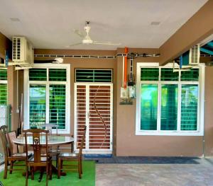a dining room with a table and chairs and windows at ST2166 Arfa Permata Homestay in Kampong Solok