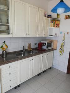 een keuken met witte kasten, een wastafel en een magnetron bij CASA SIMONE in Porto San Giorgio