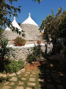 um edifício com duas cúpulas brancas e flores num quintal em Il Trullo del Cadetto em Francavilla Fontana