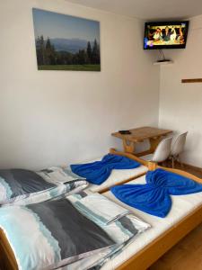 two beds in a room with a desk and a television at Agroturystyka u Czepiela in Ochotnica Górna