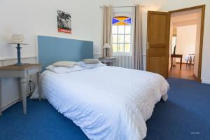 1 dormitorio con cama blanca, mesa y ventana en Auberge du Manoir d'Archelles, en Arques-la-Bataille