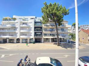 two people riding bikes in front of a building at Studio rénové lumineux proche plage et marché, 4 couchages, balcon, La Baule - FR-1-245-46 in La Baule