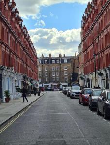 a man walking down a city street with parked cars at Stunning 1 Bedroom in Stunning Location - Mayfair Area in London