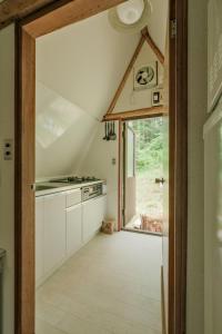 eine Küche im Dachgeschoss mit weißen Schränken und einem großen Fenster in der Unterkunft 南箱根ツリーハウス in Kannami
