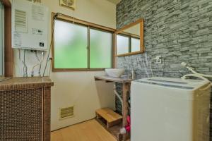 a laundry room with a washer and a stone wall at 南箱根ツリーハウス in Kannami