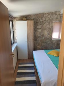 1 dormitorio con cama y pared de piedra en Happy Home LP en Gruda