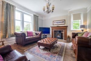 a living room with leather furniture and a fireplace at Swinside Lodge in Keswick