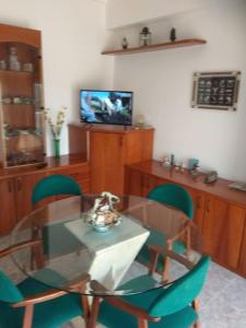 uma sala de jantar com uma mesa de vidro e cadeiras verdes em CASA LA SABONERA em Vilajuiga