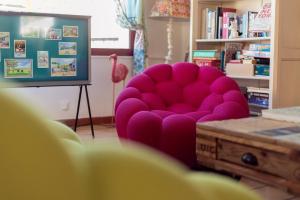 une chaise rose dans un salon avec une table dans l'établissement Hôtel La Palunette, à Saintes-Maries-de-la-Mer