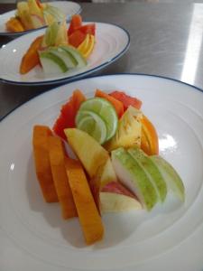 a white plate with fruits and vegetables on a table at Oruwa Boutique Villas in Arugam Bay