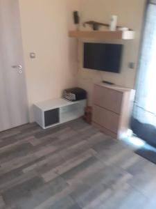 a living room with a flat screen tv and a dresser at Studio 2 ou 3 places in Verdun-sur-le-Doubs
