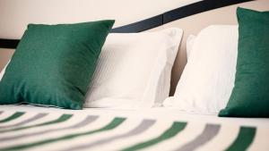 a bed with green and white pillows on it at MIIO HOTEL in San Vincenzo +11 photos