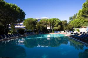 a swimming pool with chairs and trees and a building at Residence Elite in Marina di Campo