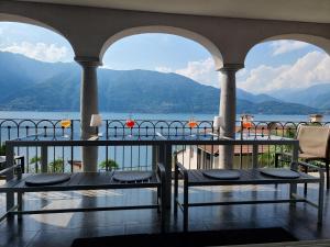 einen Balkon mit 2 Tischen und Blick auf das Wasser in der Unterkunft Wohlfühl-Oase mit Traumblick für alle Generationen inkl Aufzug in Gambarogno