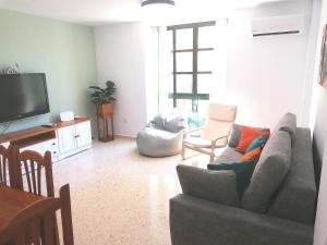 Una sala de estar con un sofá y un televisor. en Apartamento Tres Carabelas, AC, Wifi, Parking, en Sanlúcar de Barrameda