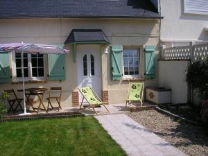 une maison avec une table, des chaises et un parasol dans l'établissement Gite du Valasse, à Gruchet-le-Valasse