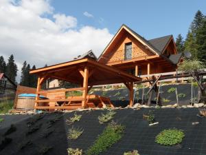 uma casa de madeira com um pavilhão à sua frente em Domki pod Pilskiem em Korbielów