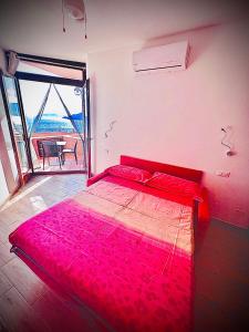 un letto rosso in una stanza con una grande finestra di Una finestra sul Blu a Teulada