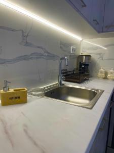 um balcão de cozinha com um lavatório de aço inoxidável em Haris white apartment em Roussospítion