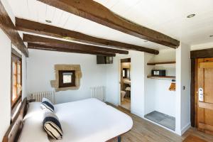 a bedroom with a white bed and wooden beams at Casa Rural Arotzenea in Hondarribia