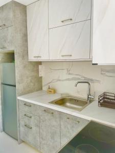 uma cozinha com armários brancos, um lavatório e um frigorífico em Haris white apartment em Roussospítion