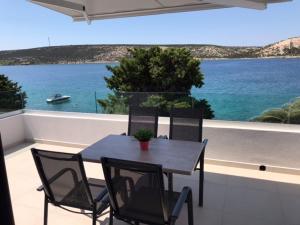 una mesa y sillas en un balcón con vistas al agua en Apartments Haramincic M&B, en Stara Novalja