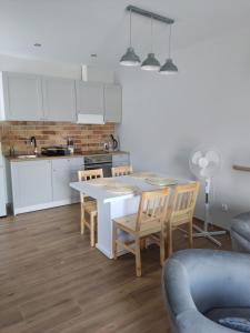 a kitchen with white cabinets and a table and chairs at Apartament u Piotra in Piotrowice