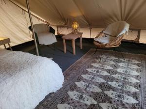 ein Schlafzimmer mit einem Bett und Stühlen in einem Zelt in der Unterkunft Hideaway Glamping in Muurame