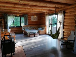 una sala de estar con sofá y hamaca en una cabaña de madera en Palmas, en Jūrkalne