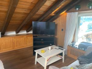 ein Wohnzimmer mit einem TV und einem Tisch in der Unterkunft Dachwohnung in der Mitte von Laax-Dorf in Laax