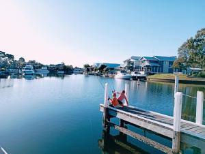 dos personas sentadas en un muelle sobre un cuerpo de agua en Captains Cove 1st Floor Spa Luxury Apartments - Free Netflix, en Paynesville