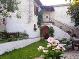 a white building with a staircase and pink flowers at The old stone house in Paramythia