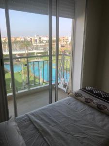 - une chambre avec un lit et une grande fenêtre dans l'établissement Bel appartement pied sur mer vue imprenable sur piscine et jardins, à Sidi Rahal