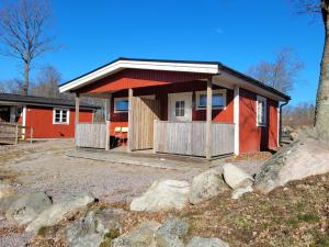 a small red house with a porch and some rocks at Tydingesjöns Camping & Festplats in Broby