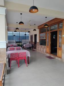 a restaurant with red tables and chairs and windows at Meghdoot river resort in Ernakulam