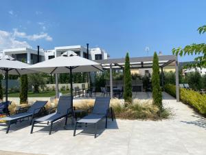 a group of chairs and umbrellas in front of a building at Olea Luxury Apartments in Nikiti