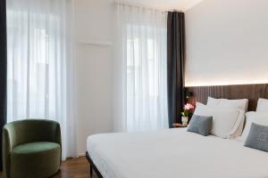 a bedroom with a large bed and a green chair at Hotel Casa Scaligeri in Sirmione