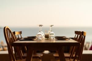 una mesa de madera con dos copas de vino. en PHEIA, Vriniotis Resorts, en Katakolon