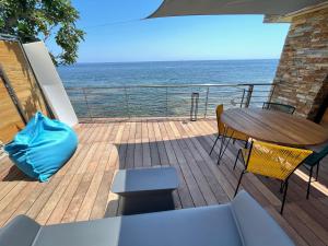 a deck with a table and chairs and the ocean at miomo bord de mer in Santa-Maria-di-Lota