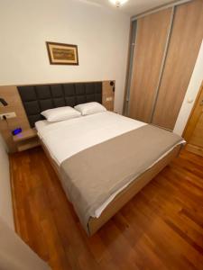 a bedroom with a large white bed with a wooden floor at Meridian Hotel in Budva