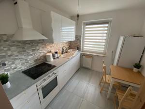 une cuisine avec des armoires blanches, un évier et un réfrigérateur dans l'établissement Pokoje Polinezyjska, à Varsovie 18 autres photos