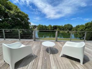 2 chaises blanches et une table sur une terrasse dans l'établissement Gîte de charme bord de Meuse, à Namur