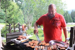 Ein Mann kocht Fleisch auf einem Grill in der Unterkunft Grubhof Appartements in Ellmau