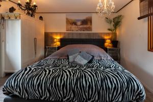 a zebra print bed in a bedroom with a chandelier at Private Chalet Heppie People in Doornspijk