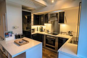 a kitchen with black cabinets and white counter tops at The Penthouse Canterbury - Cathedral View in Canterbury