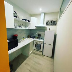 a small kitchen with white cabinets and a refrigerator at T2 hypercentre Libourne 5 min St Emillon in Libourne