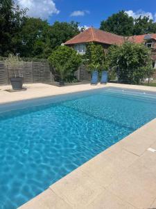 a swimming pool with two chairs and a house at Chambre d'Hotes La Chaiserie in Romeries