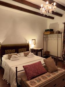 um quarto com uma cama com lençóis brancos e um lustre em A casa del Nonno em Isnello