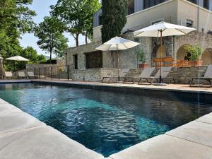 a swimming pool with chairs and umbrellas in front of a building at Hôtel Villa Walbaum in Vallon-Pont-dʼArc