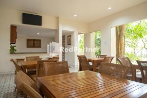 a dining room with tables and chairs and windows at Villa Dora Jogja near Malioboro Area Mitra RedDoorz in Sentool